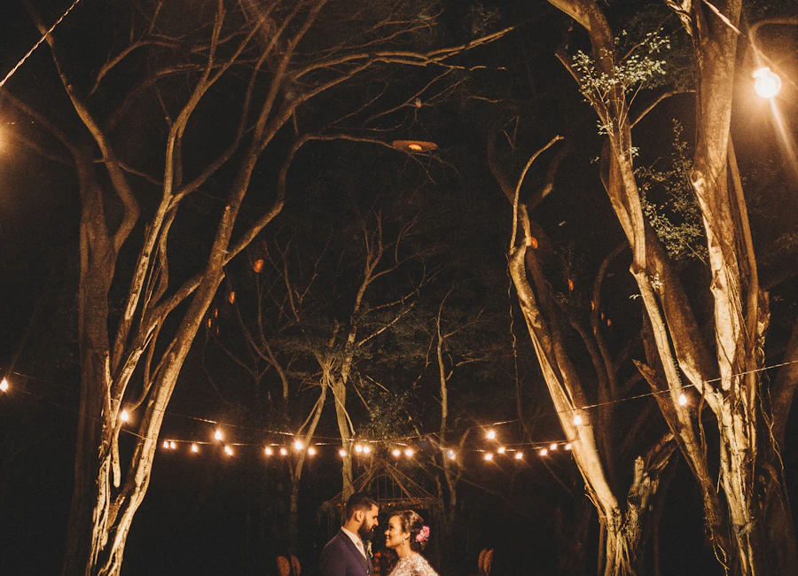 Casal em festa de casamento ao ar livre sob luzes quentes