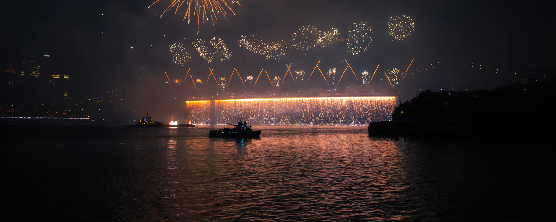 Show pirotécnico refletido sobre a água durante uma virada de ano